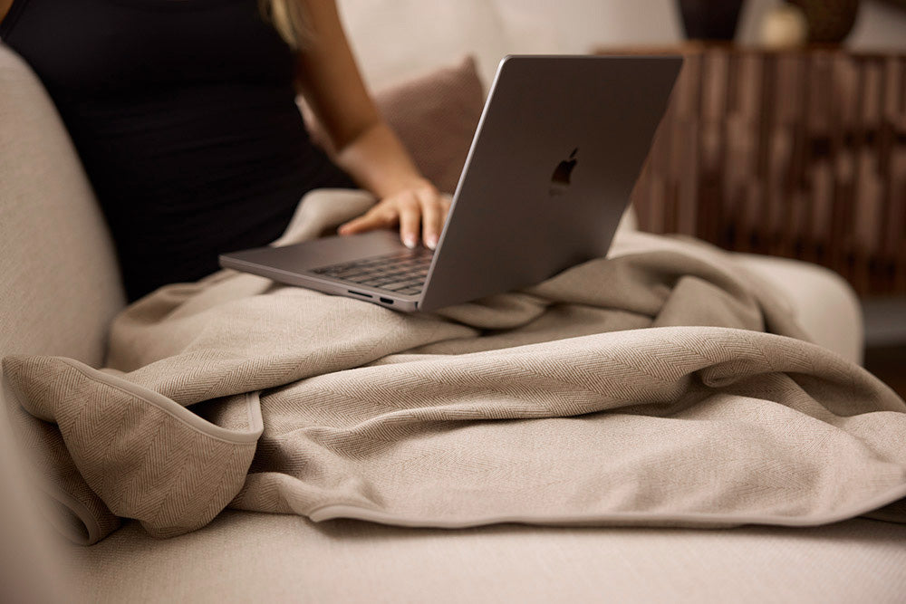 Person using a laptop and EMF blanket sitting on a couch